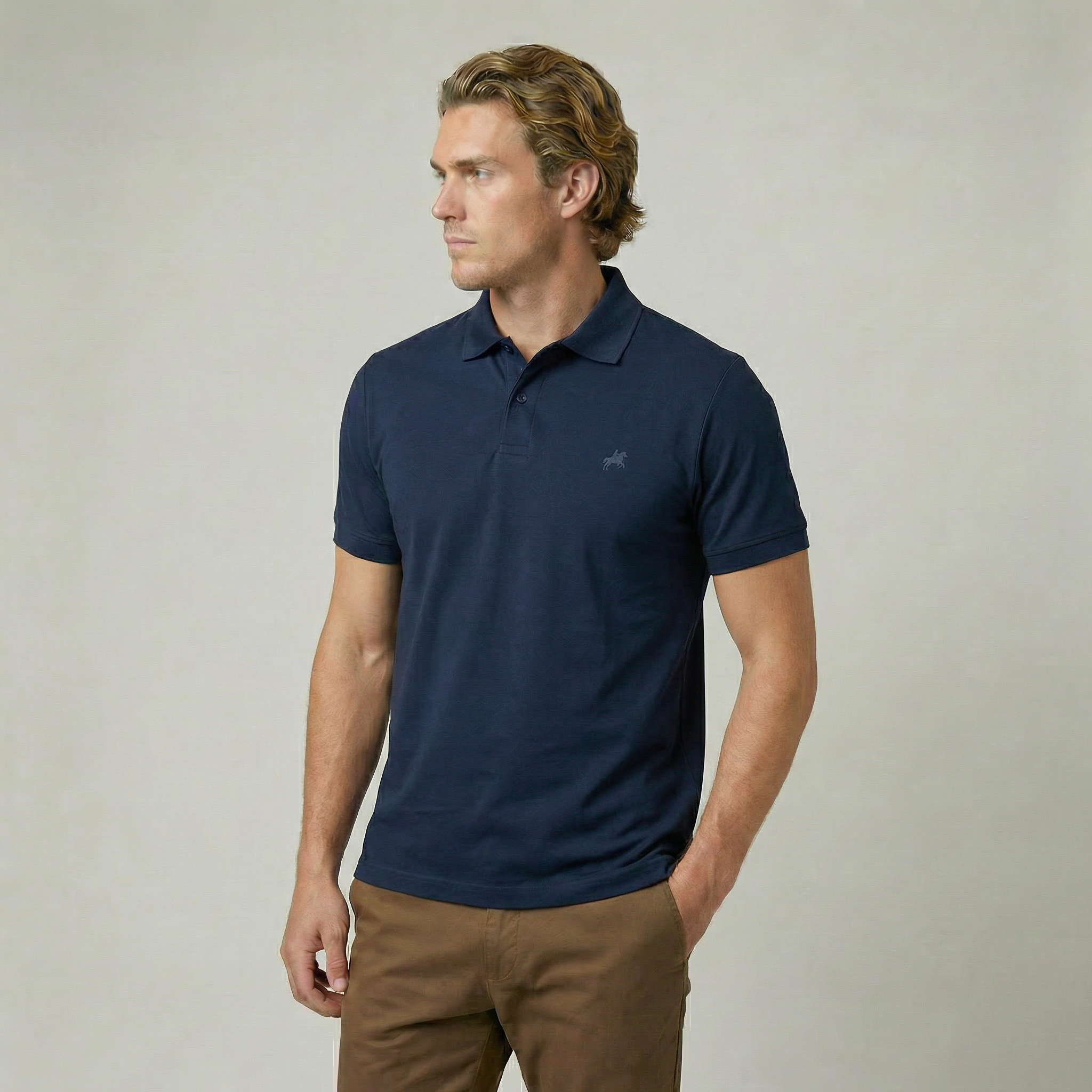 Man wearing a navy polo shirt with a logo on a plain background