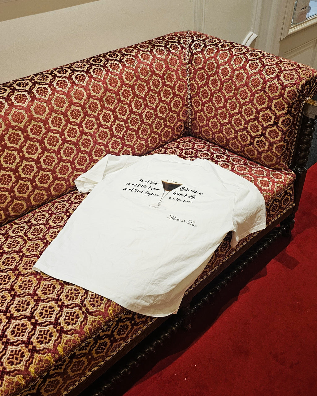White t-shirt with text on a patterned red and brown sofa.