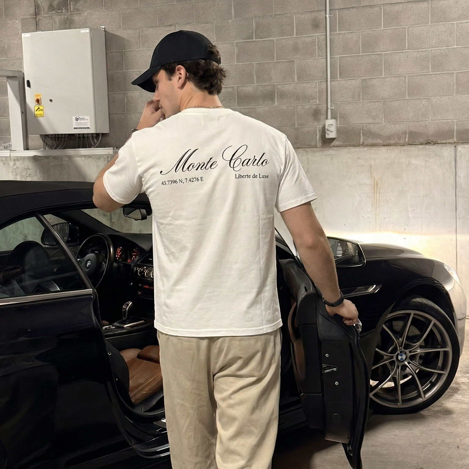 Man in a garage wearing a white t-shirt with branding.